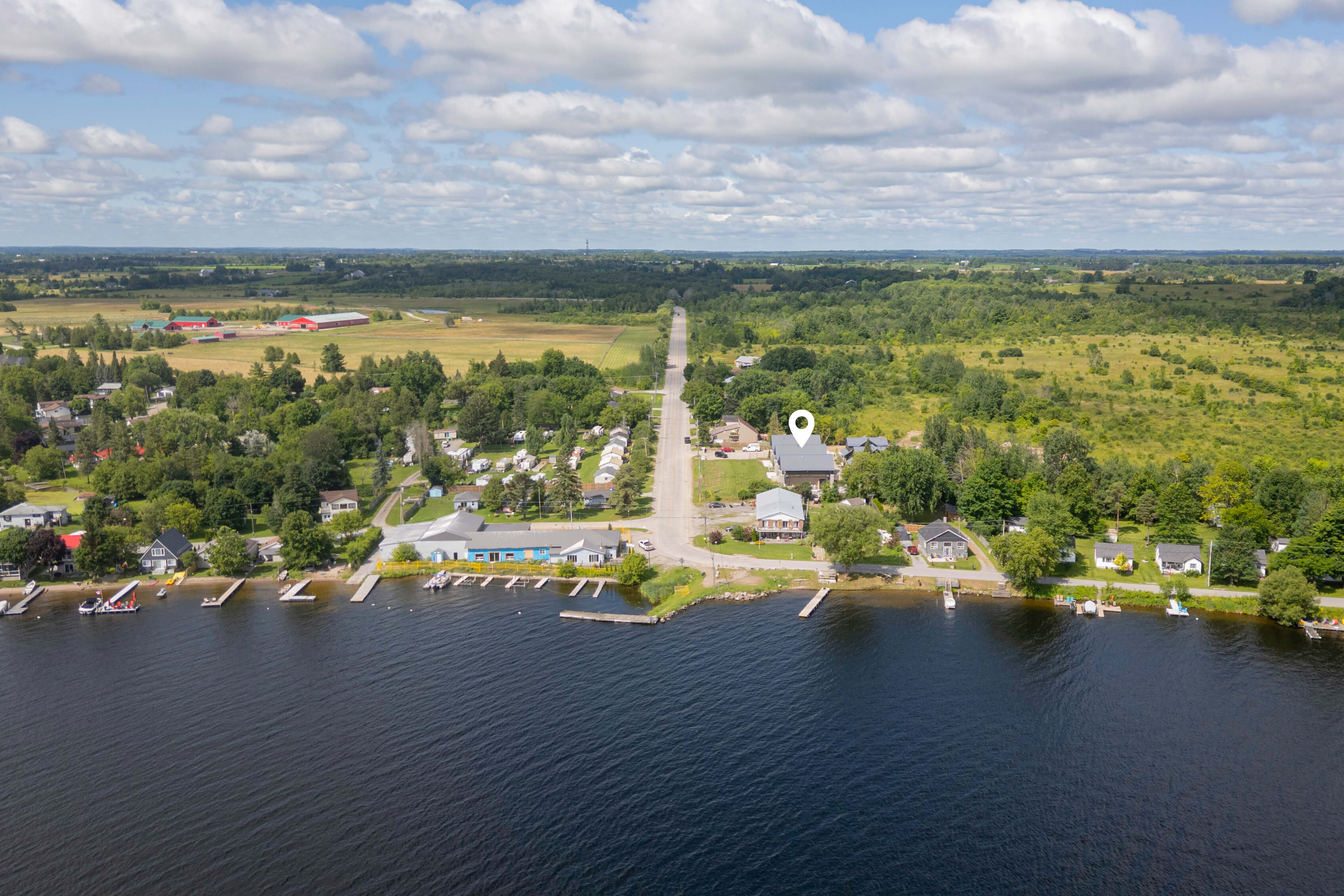 Aerial view of Airbnb rental near Ontario lakeside village — property marked with pin near waterfront docks, open countryside and lake beyond