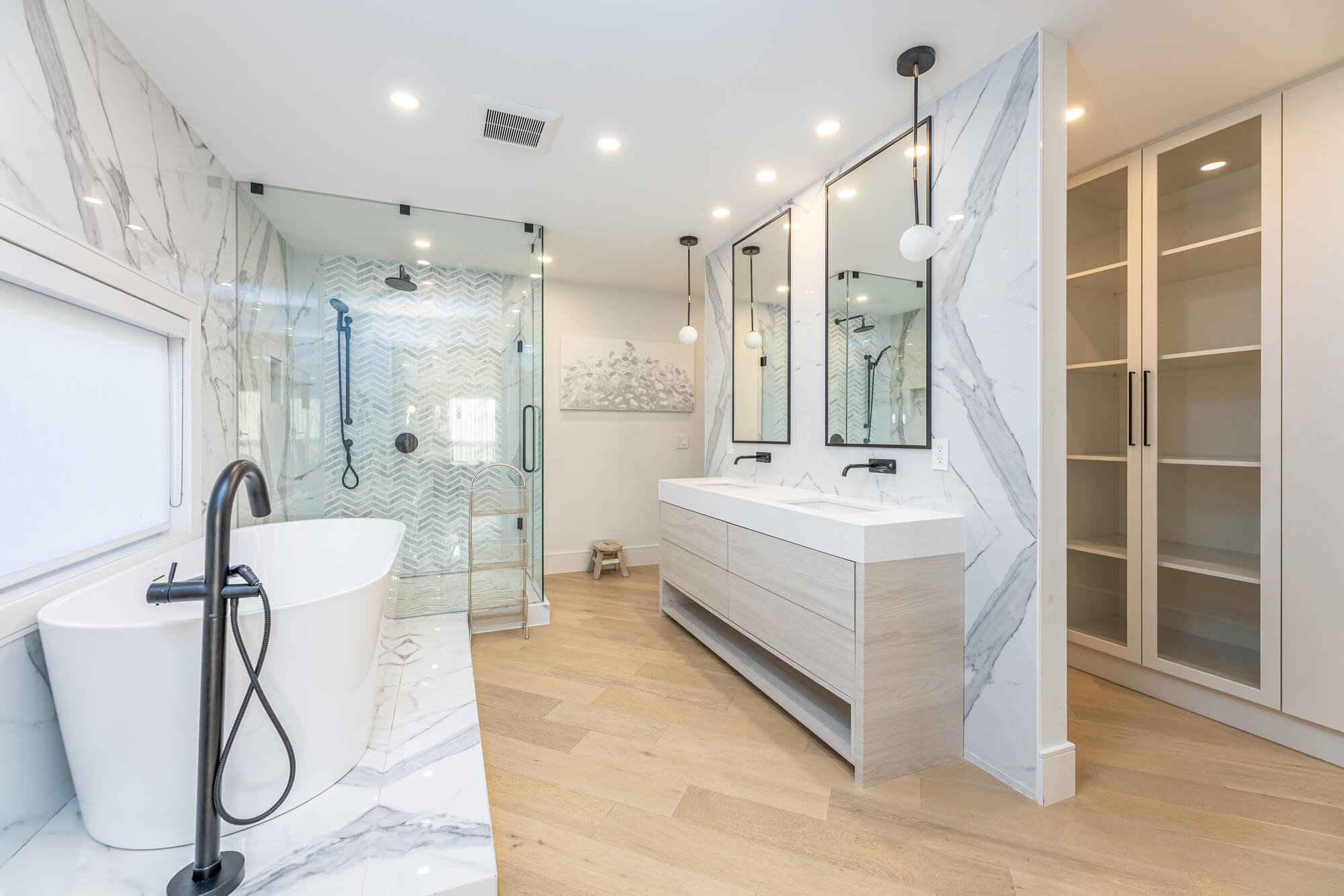 Luxury ensuite bathroom in Ontario VRBO rental — freestanding soaker tub, glass walk-in shower with chevron tile, double vanity and marble feature wall