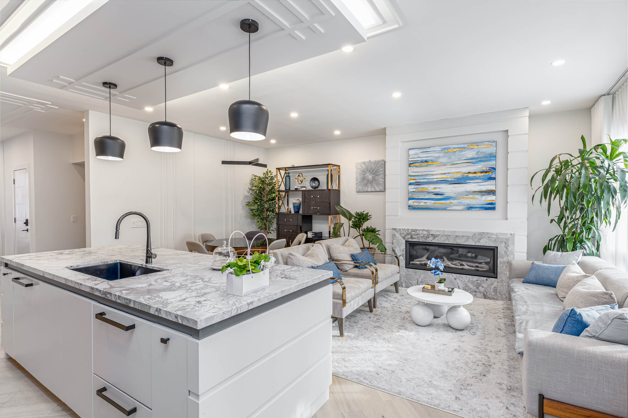 Cozy Airbnb living room in Ontario — blue linen sofas, built-in window seat with storage, floor-to-ceiling windows with stone column exterior and backyard views